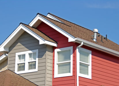 Gutters installed on a two-story red-and-gray home.