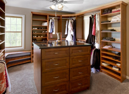 Closet and shelving installation with wood-grain shelving and large dresser in the middle.