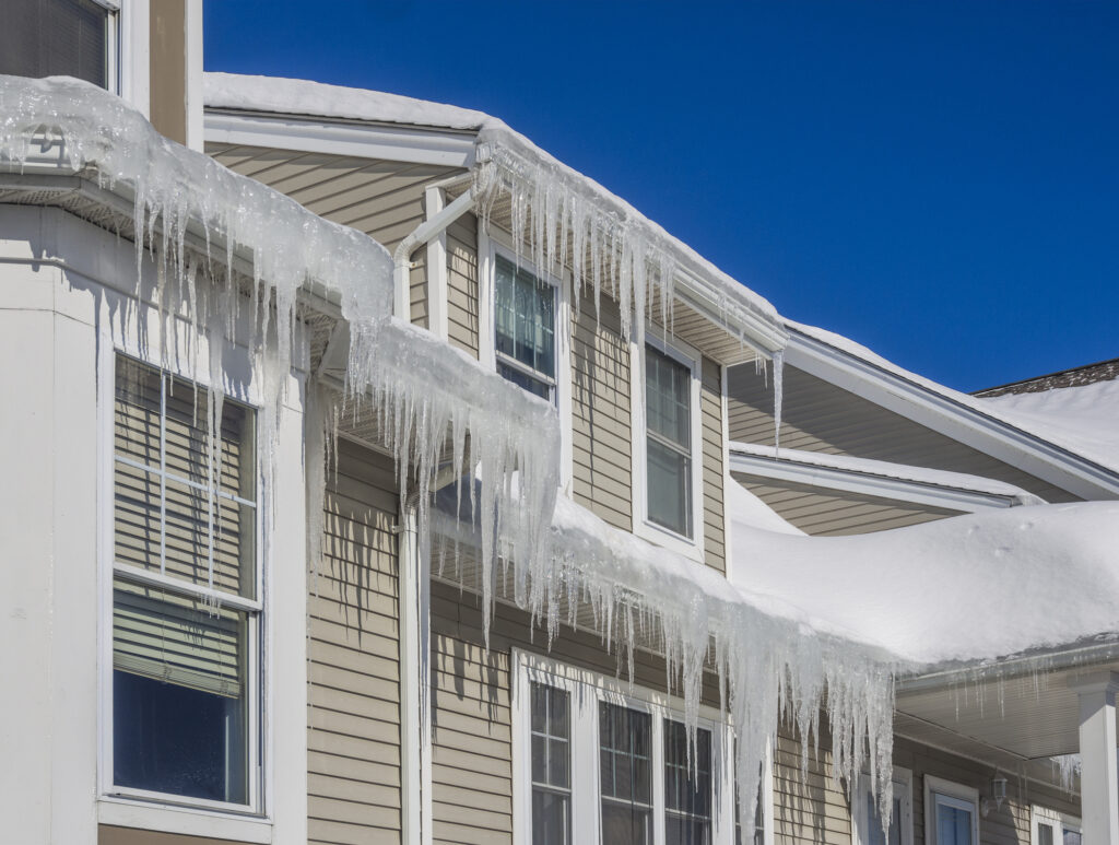Ice dams along gutter system on a home. Huge icicles hanging down from second-story gutters.