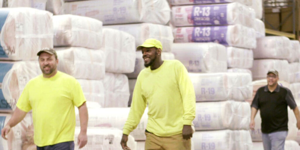 Happy Town Building Systems employees, with lots of insulation packed in a warehouse behind them