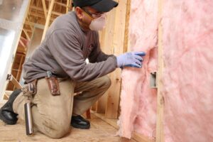 Worker installing insulation in wall